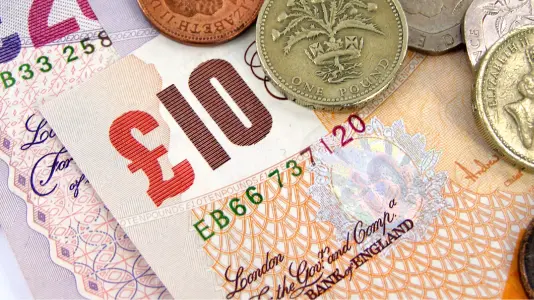 An image focused on 10 British pound banknote with some coins above it