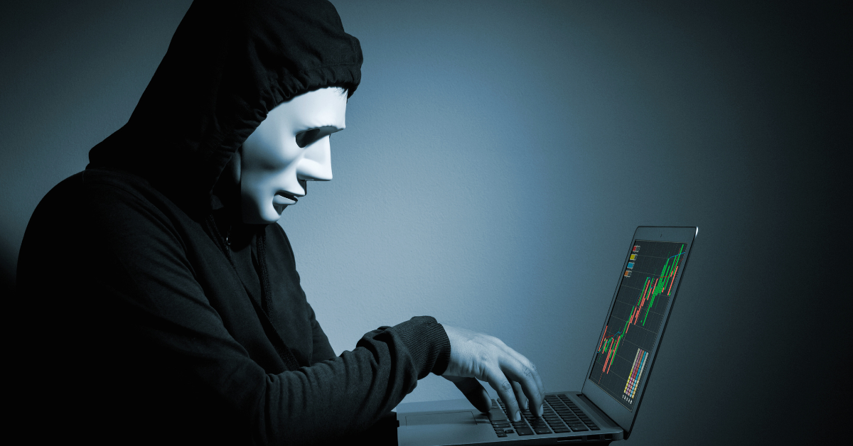 An image of a mysterious and suspicious person in front of a trading device, representing the signs of scam brokers