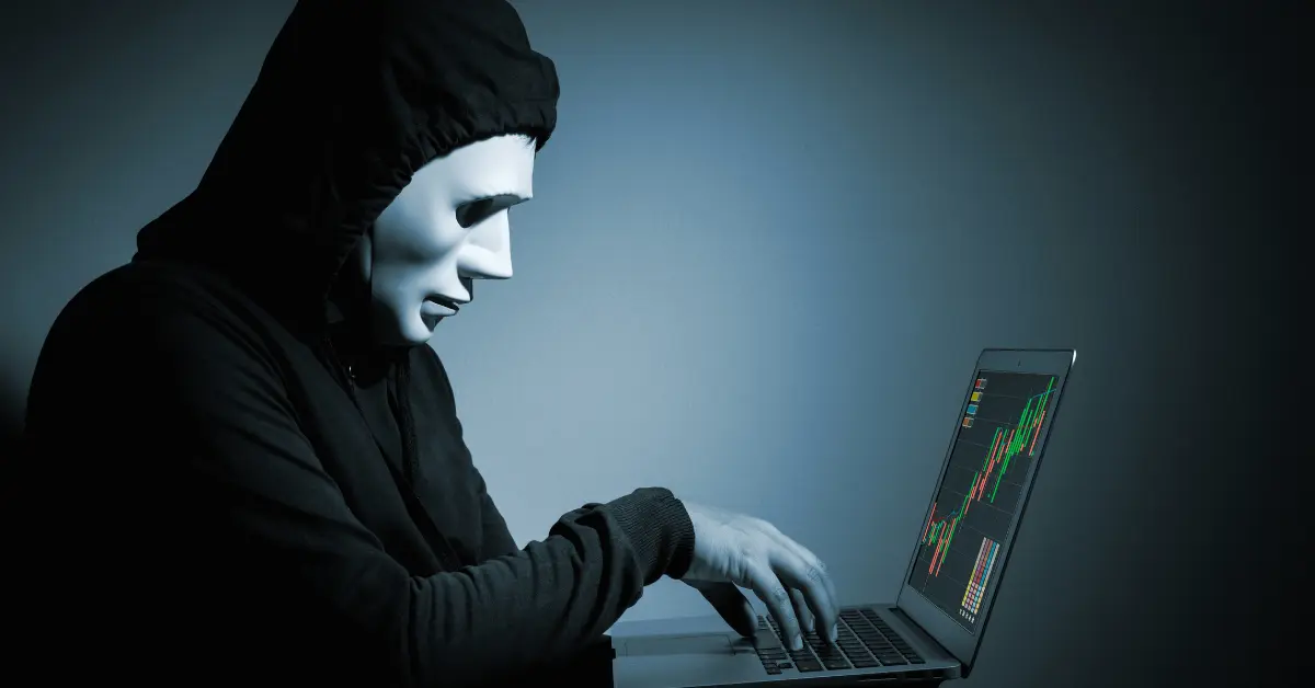 An image of a mysterious and suspicious person in front of a trading device, representing the signs of scam brokers