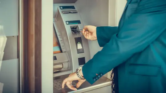 An image of a person withdrawing money through an automated teller machine (ATM)